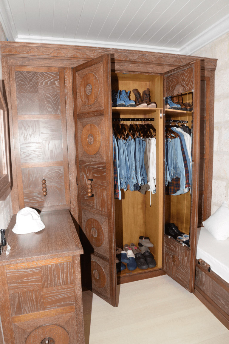A closet ready for a fresh start An open wooden wardrobe with neatly hung clothes and shoes, representing a wardrobe reset
